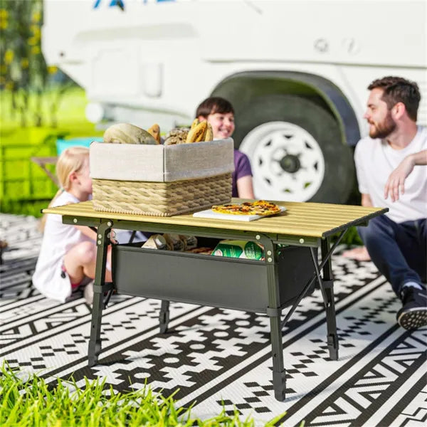 Family having a picnic around a folding camping table next to an RV